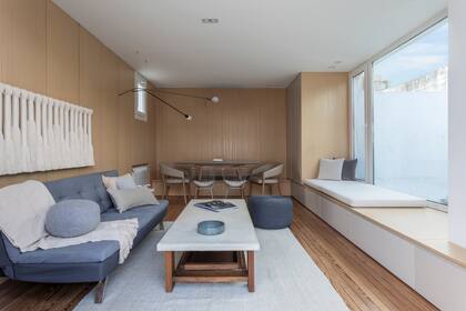 Al fondo, el comedor. Lámpara de pared (Federico Churba). Sillón (Tapicería Carlos Méndez) con manta (Maimará) y almohadones (Lote Propio). Obra textil (Cristina Codern). Puf (Mausy Design).