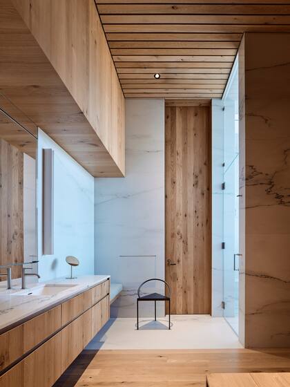 El baño del dormitorio principal combina madera y mármol para crear una atmósfera cálida y sofisticada.