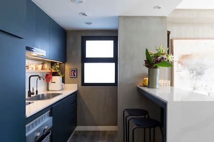Mesada y alzada en Silestone con pileta de acero inoxidable (Johnson Acero). Banquetas ‘Oui’ (Ten Estudio). El rallador de queso rojo suma una nota de color que evoca los domingos de la infancia, cuando la bisabuela de Martina amasaba para todos.