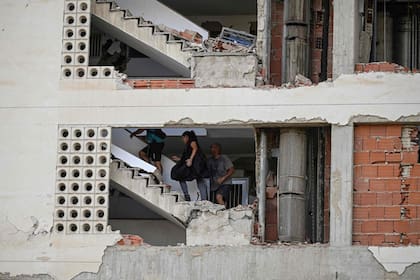 Personas caminan dentro de un edificio de departamentos dañado tras un terremoto en Catia La Mar